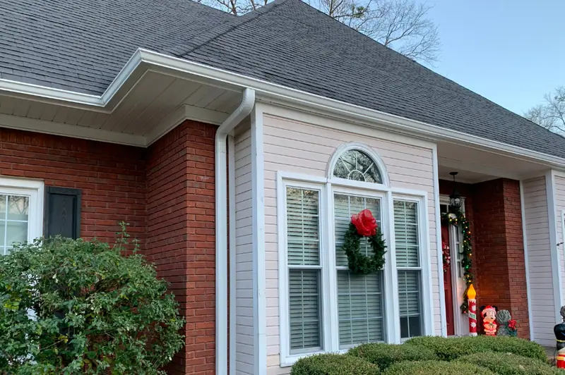 White gutter and downspout on a brick and lap-siding home, a Mosqueda Construction gutter job