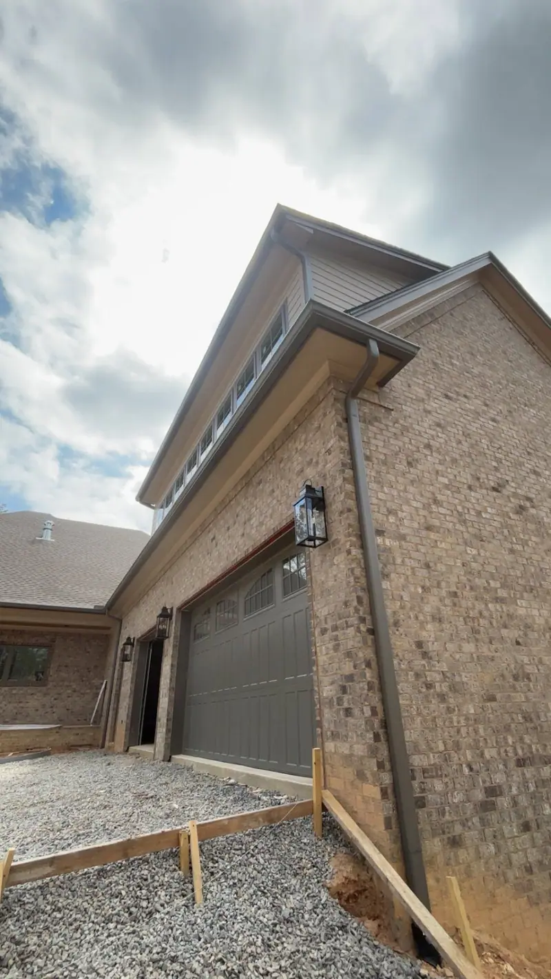 Bronze gutter and downspout at the garage corner of a new brick home, a Mosqueda Construction gutter job