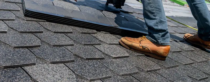 Roofer nailing down asphalt shingles with a pneumatic nailer