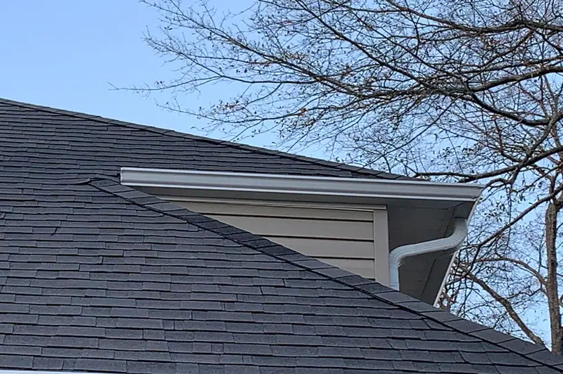Dark architectural shingles meeting a white gutter at the roof edge, a Mosqueda Construction job