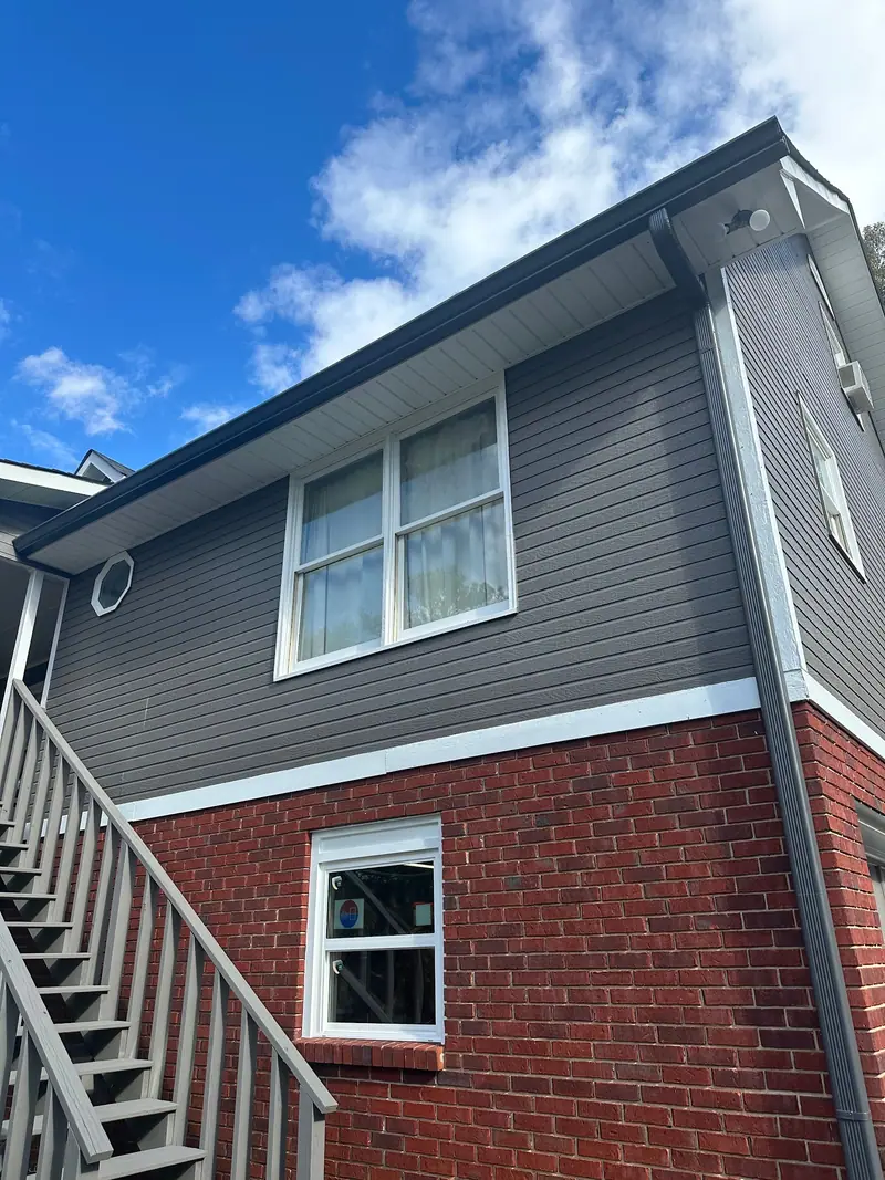 Gray lap siding above red brick with white trim and a new window, a Mosqueda Construction siding job near Birmingham, AL