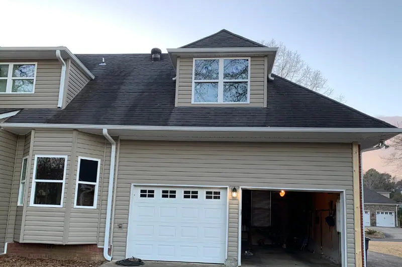 Tan lap siding, white gutters and new windows on a two-storey home with a garage, a Mosqueda Construction job
