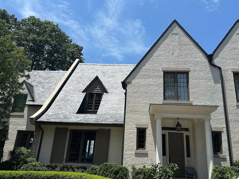 White painted-brick Tudor home with a slate roof and dark gutters and downspouts, a Mosqueda Construction job in the Birmingham area